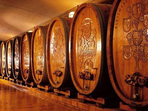 Rangée de grands tonneaux en bois avec des motifs sculptés dans une cave à vin.