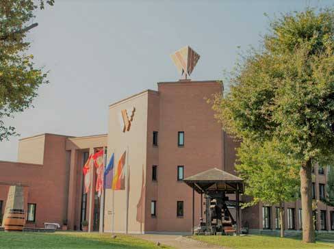 Bâtiment en briques avec un grand logo 'Y', des drapeaux et des arbres.