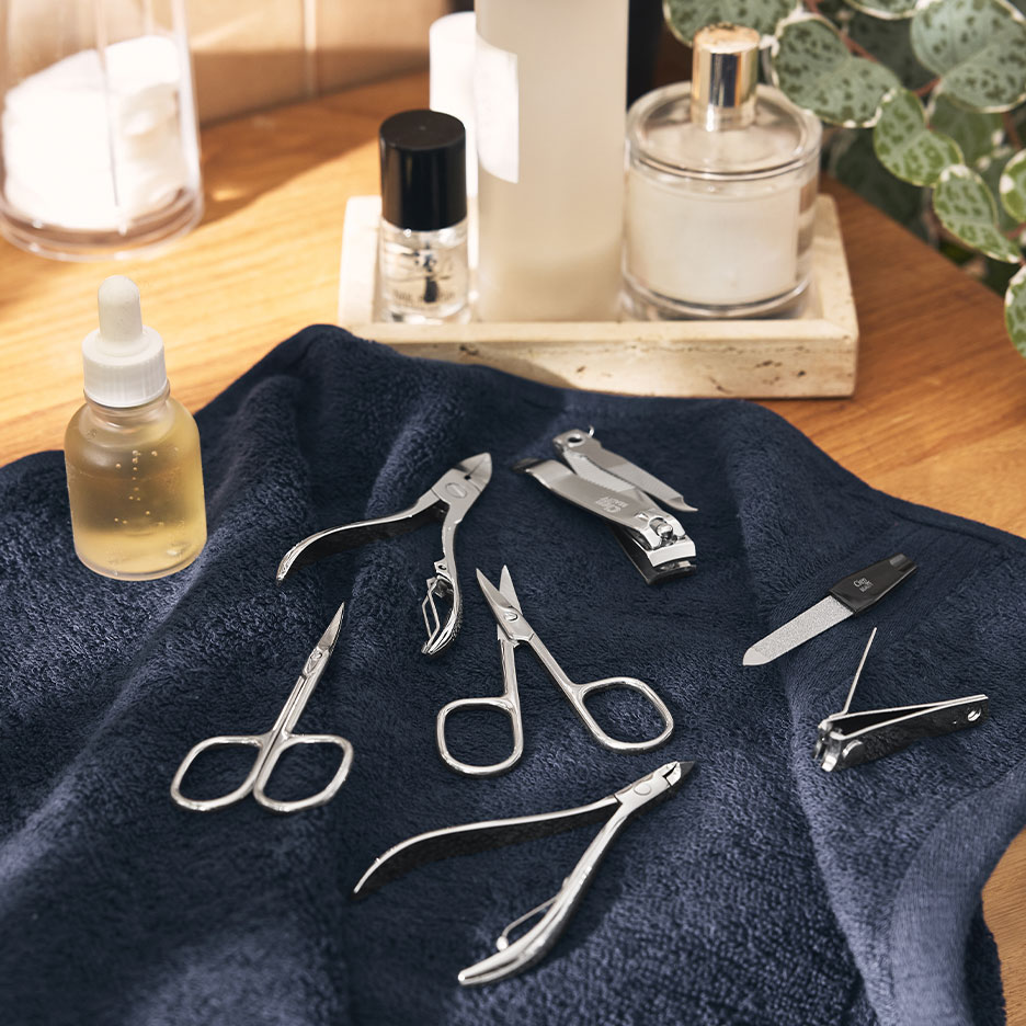 Kit de manucure avec coupe-ongles, ciseaux et limes sur une serviette bleu foncé.