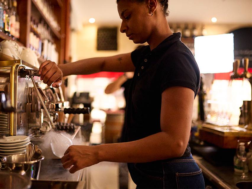 Barista préparant une boisson avec de la vapeur d'une machine à expresso.