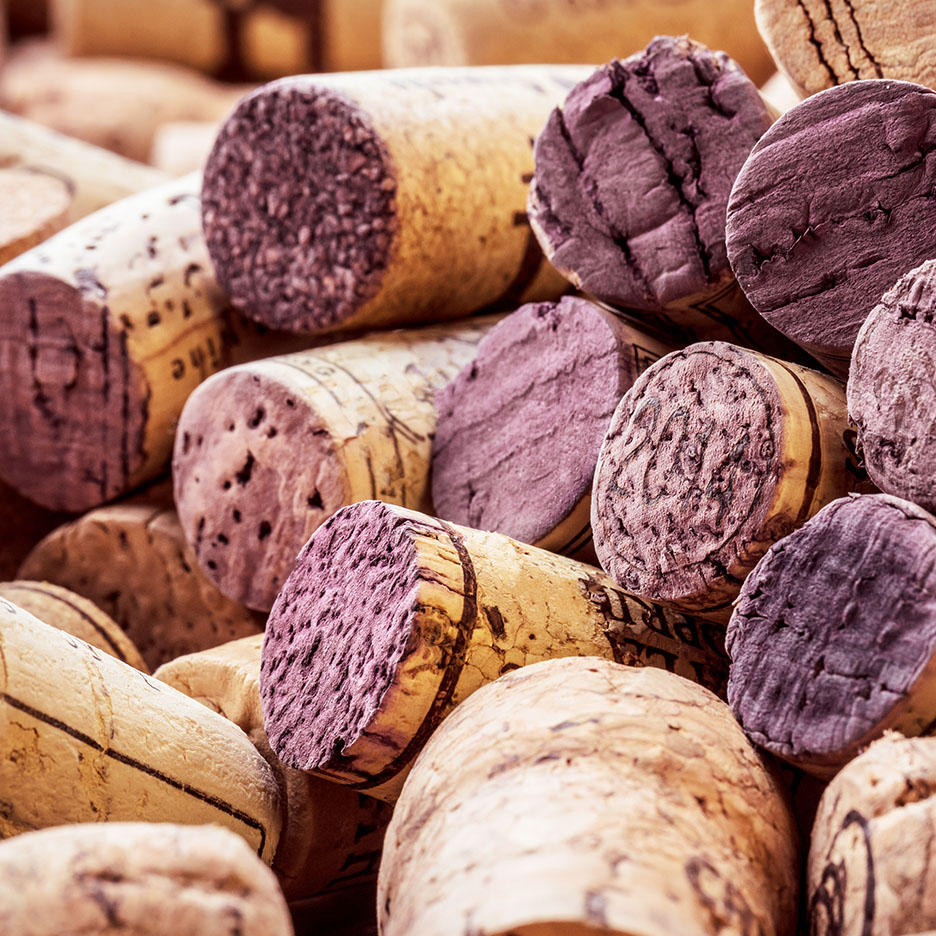 Gros plan sur un tas de bouchons de vin, certains teintés de violet par le vin rouge.