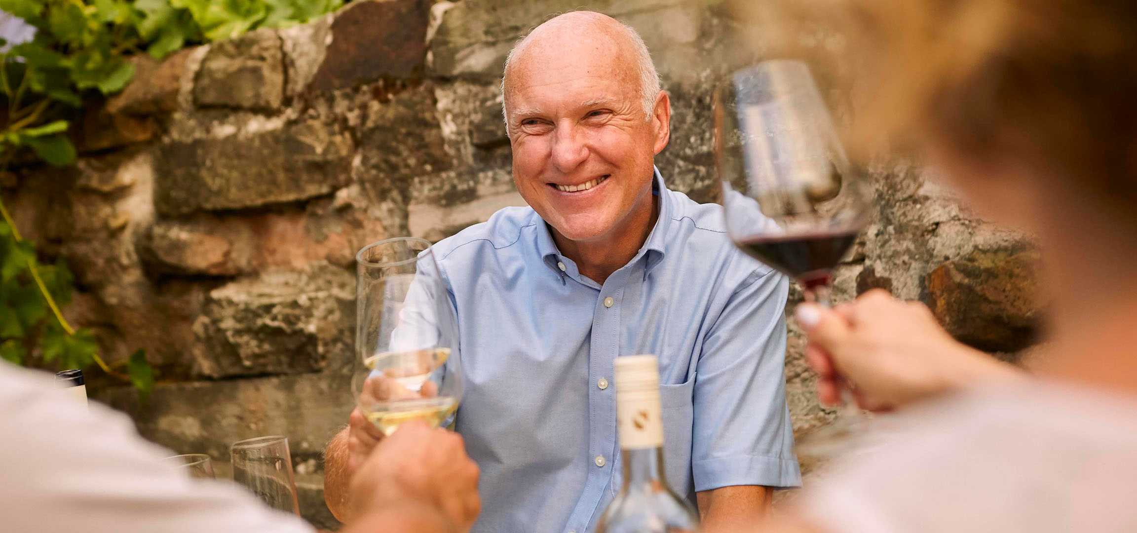 Homme souriant buvant du vin rouge en plein air.