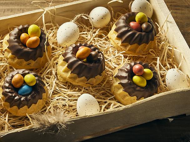 Mini gâteaux de Pâques au chocolat avec des œufs colorés dans une boîte en bois.