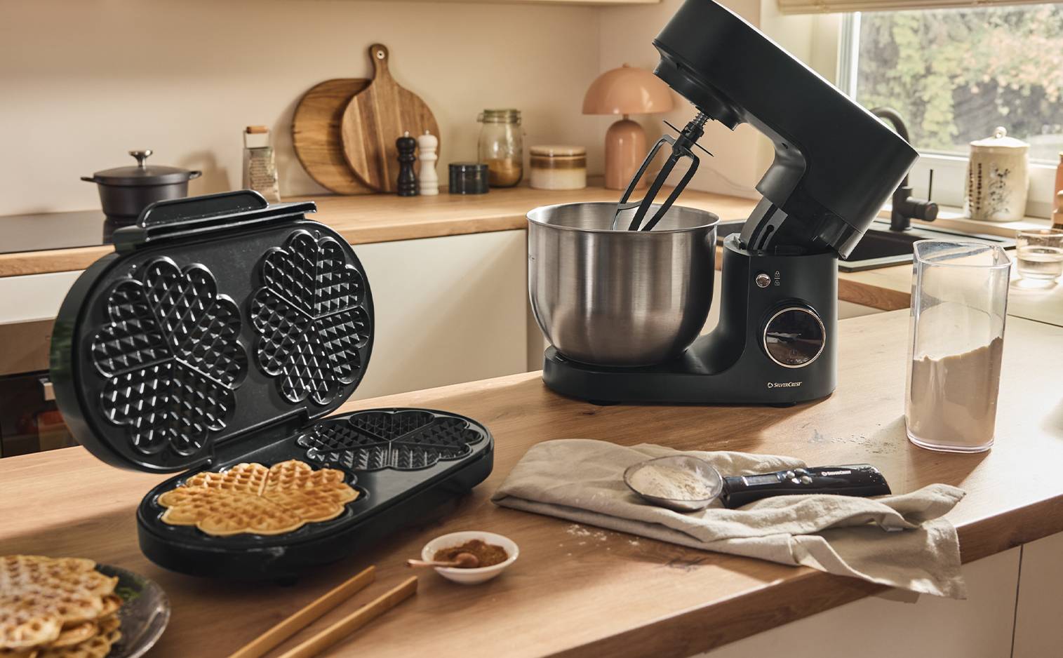 Gaufrier ouvert avec une gaufre et robot pâtissier sur un comptoir de cuisine en bois.