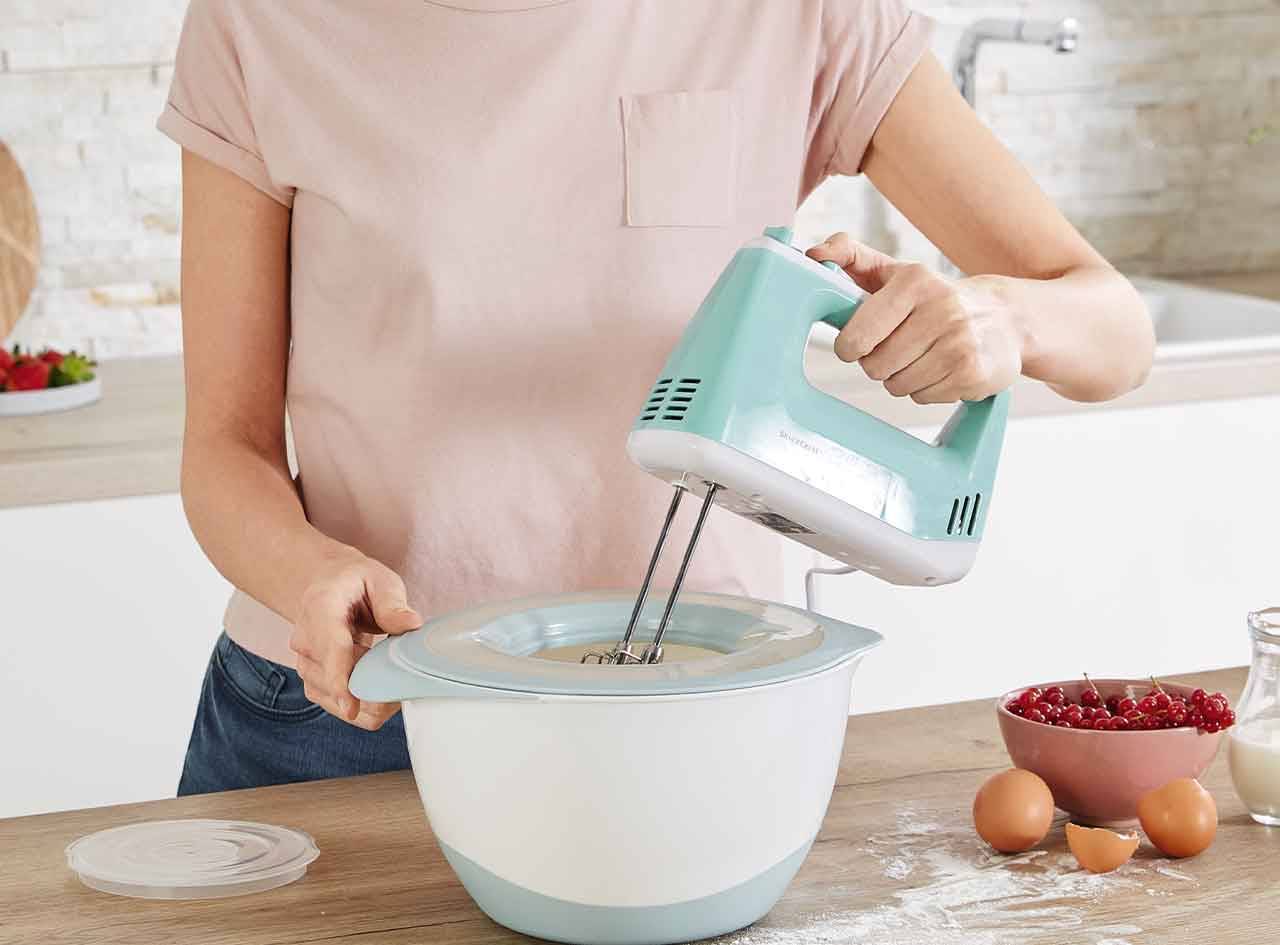 Une femme utilise un batteur sur socle Swan pour préparer un gâteau dans sa cuisine.