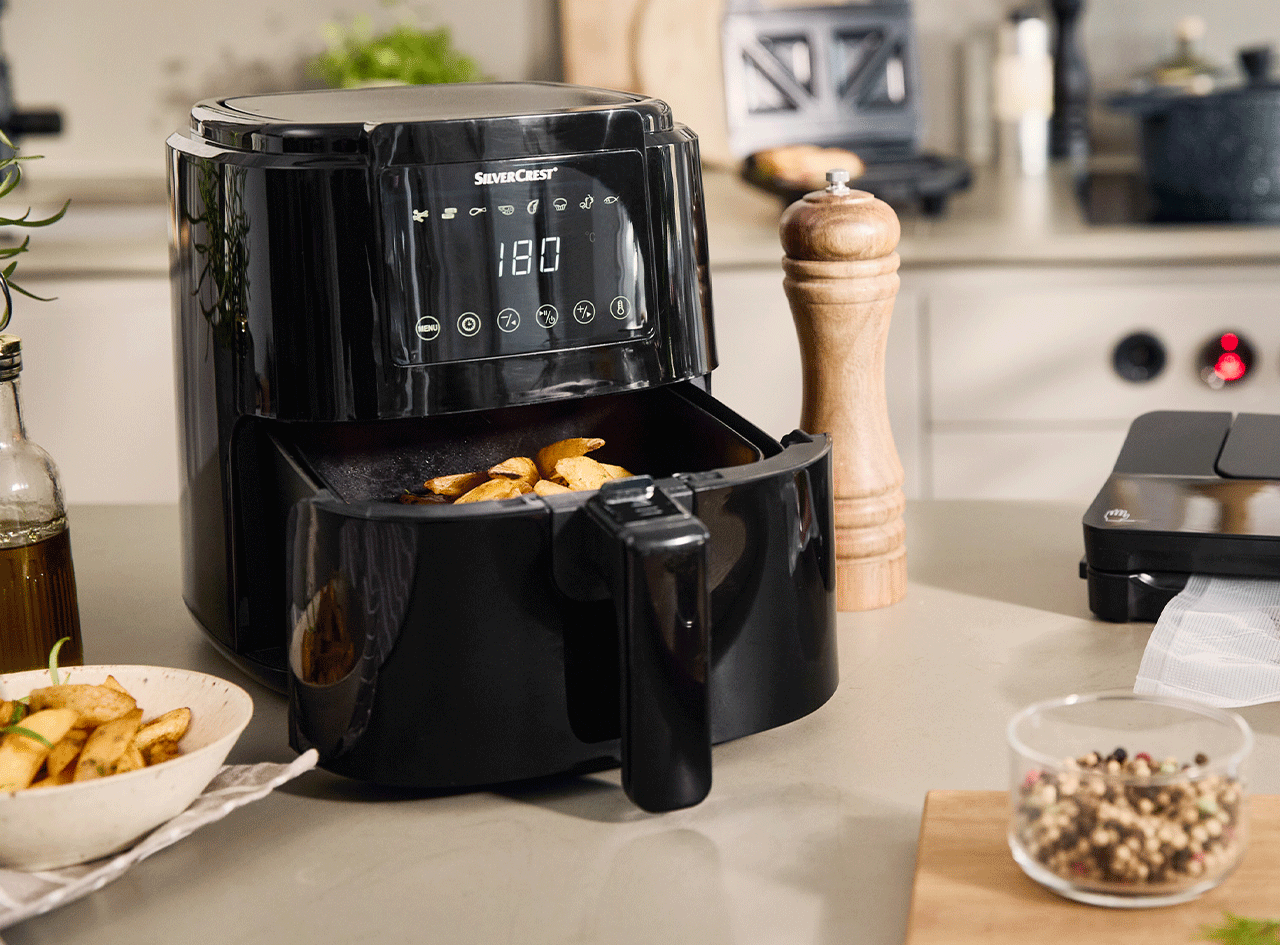 Une friteuse à air chaud SilverCrest noire avec des frites à l'intérieur, sur un comptoir de cuisine.