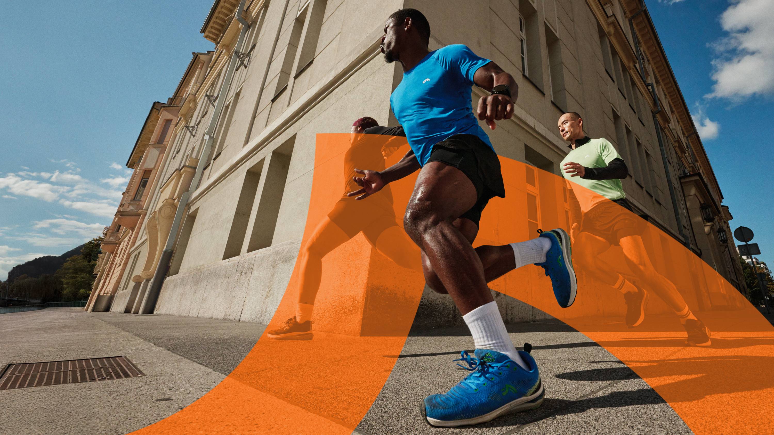 Deux hommes courent en tenue de sport sur un trottoir ensoleillé.