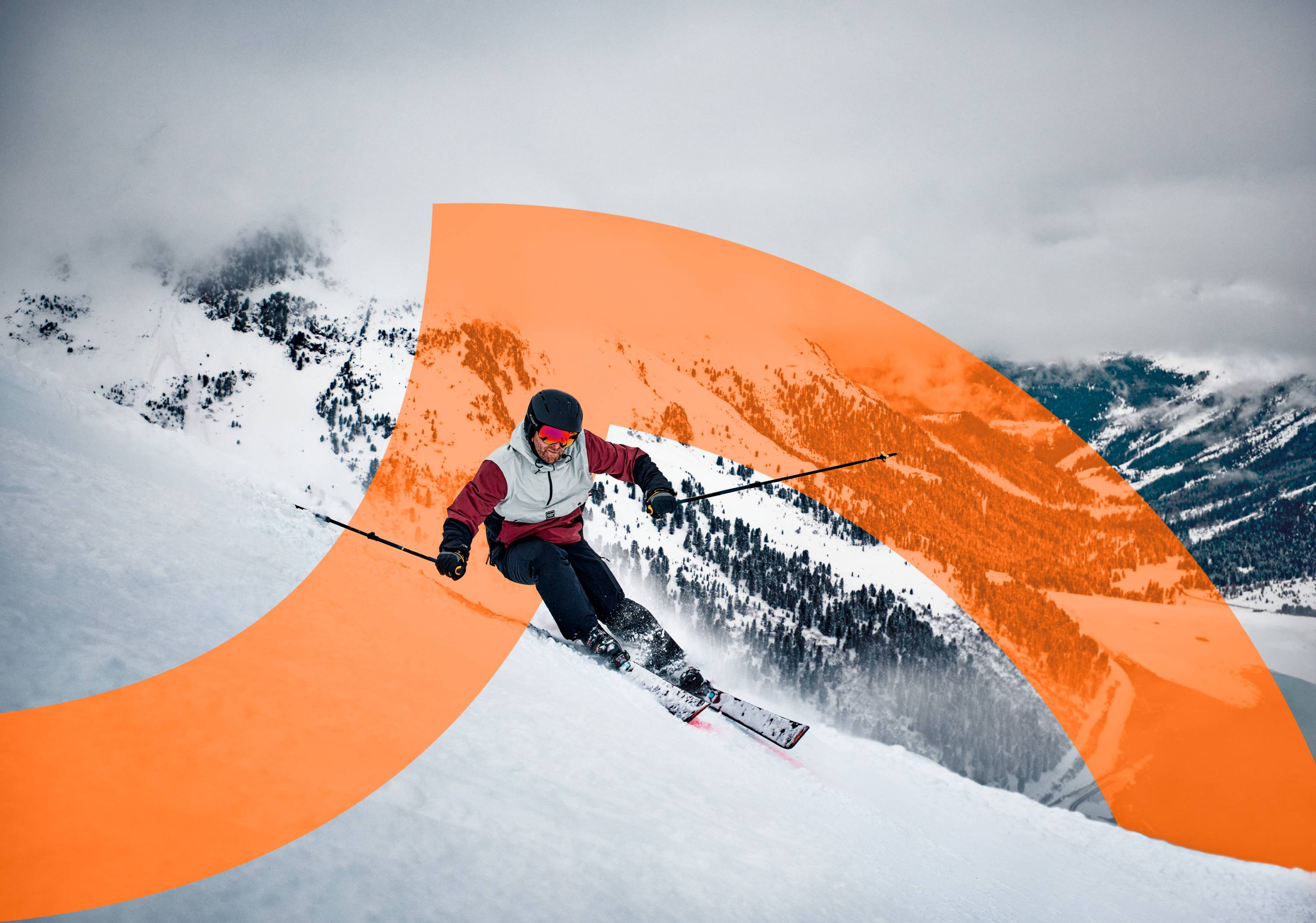 Skieur en tenue de ski colorée dévalant une pente enneigée avec des montagnes en arrière-plan.