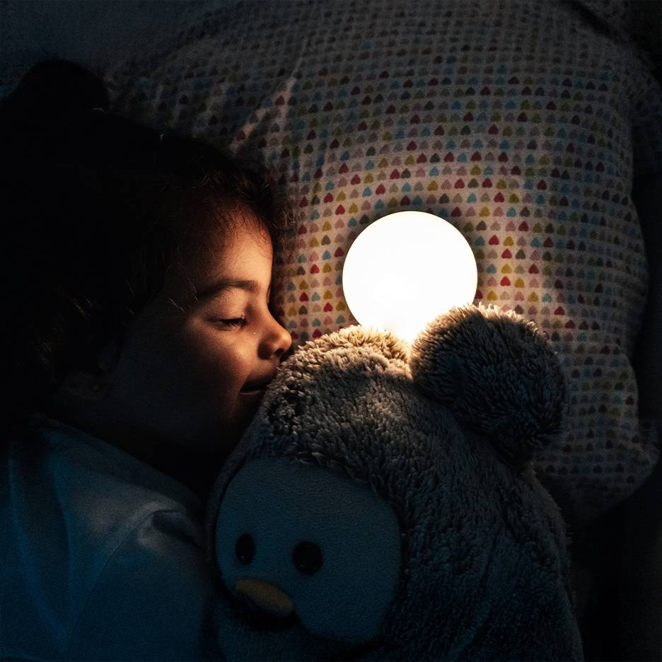 Fille dormant avec une peluche et une veilleuse lumineuse.