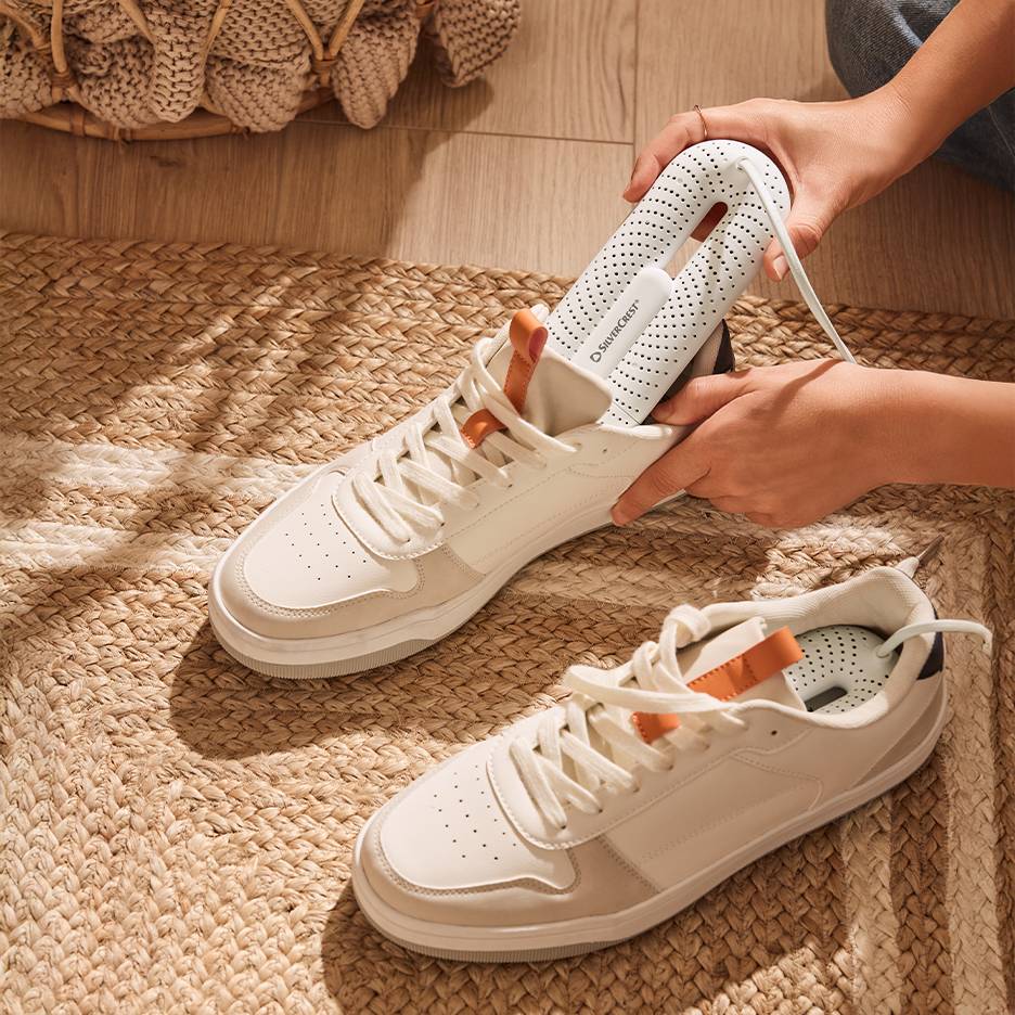 Sèche-chaussures Silvercrest dans des baskets blanches sur un tapis tressé.