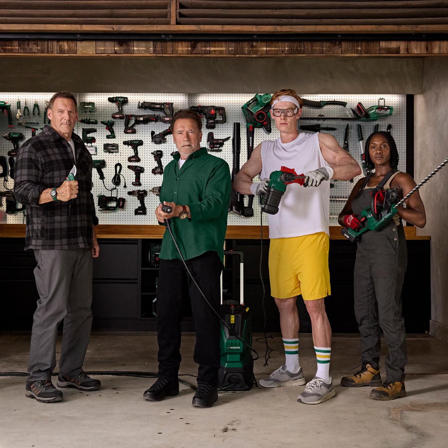 Quatre personnes, dont Arnold Schwarzenegger, posent avec des outils Parkside dans un atelier.