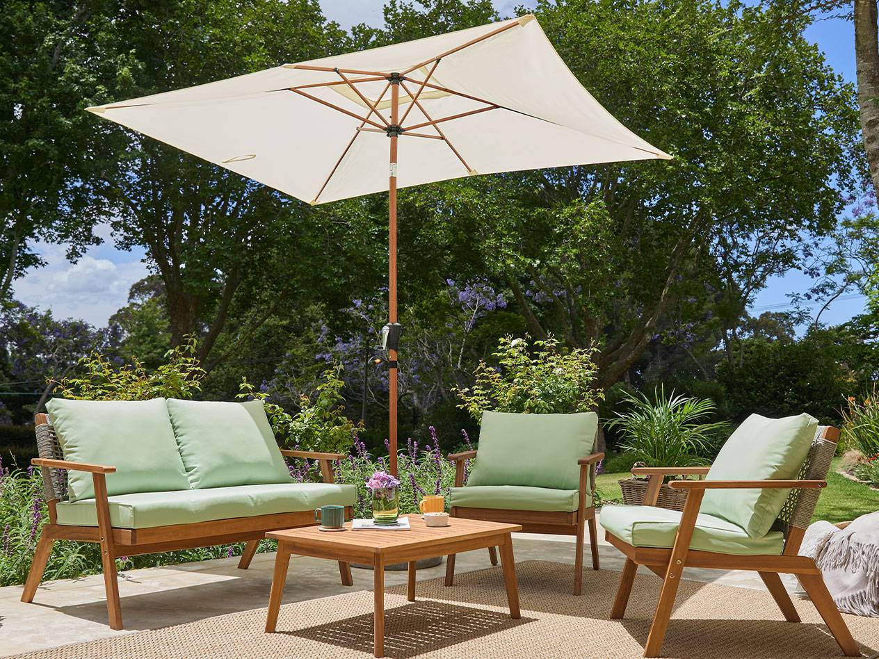 Ensemble de mobilier de jardin en bois d'acacia avec coussins verts et parasol.