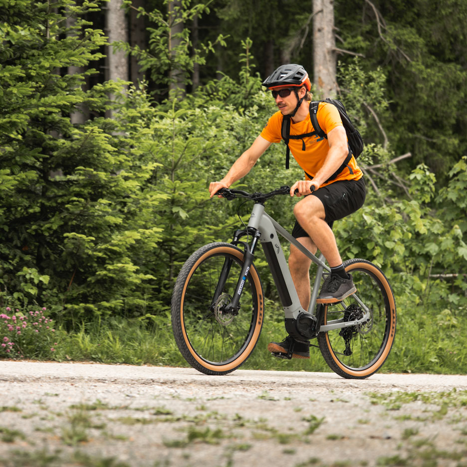 Un homme roule à vélo électrique sur un chemin forestier.