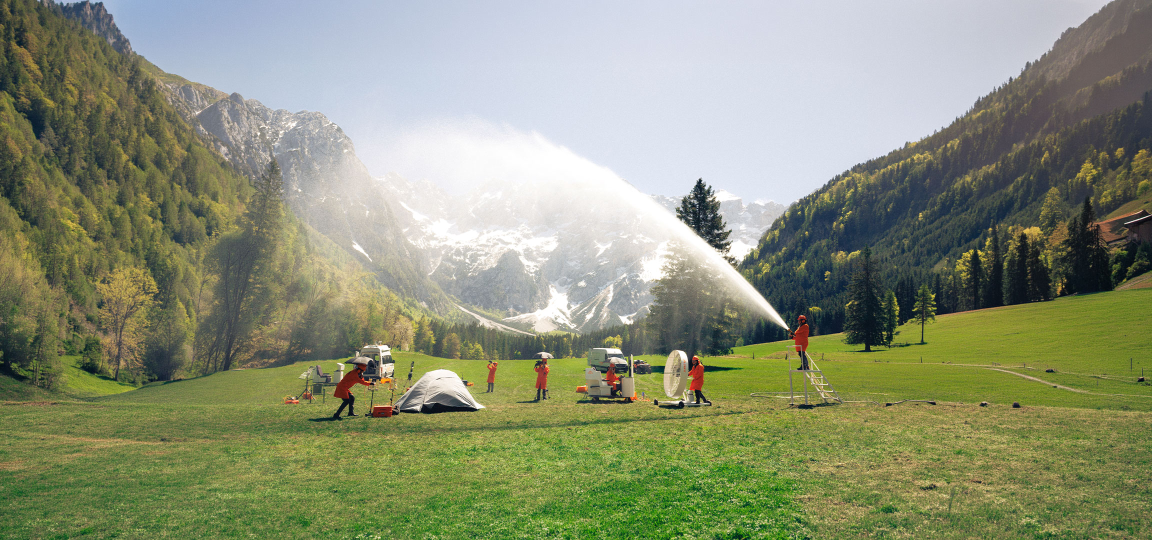 undefined: Personnes en combinaisons de protection orange testant du matériel de camping et d'extérieur dans un pré.
