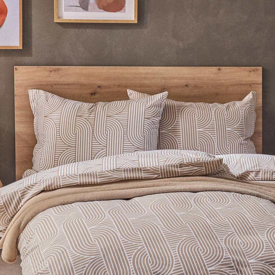 Parure de lit à motif géométrique marron et blanc, avec une couverture douce sur un lit en bois.