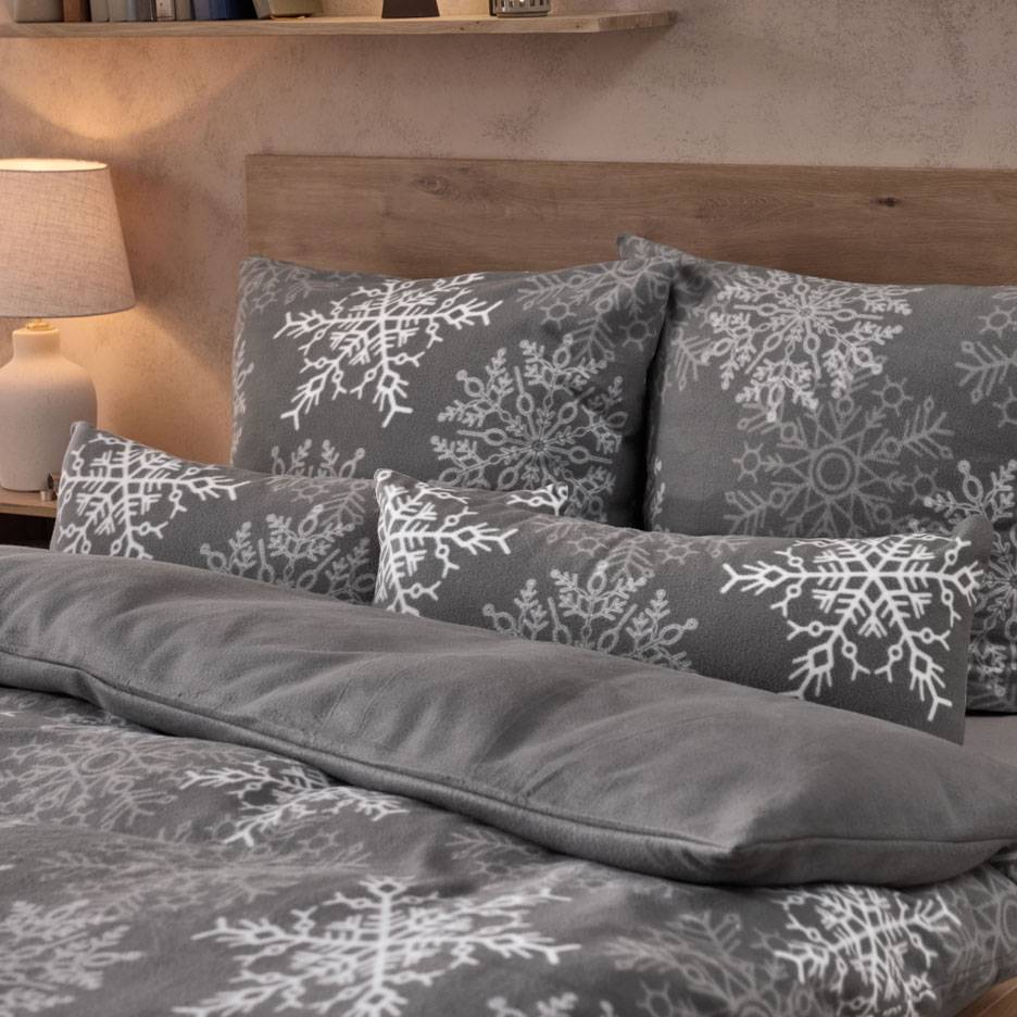 Parure de lit grise à flocons de neige blancs, avec oreillers et couverture douillette.