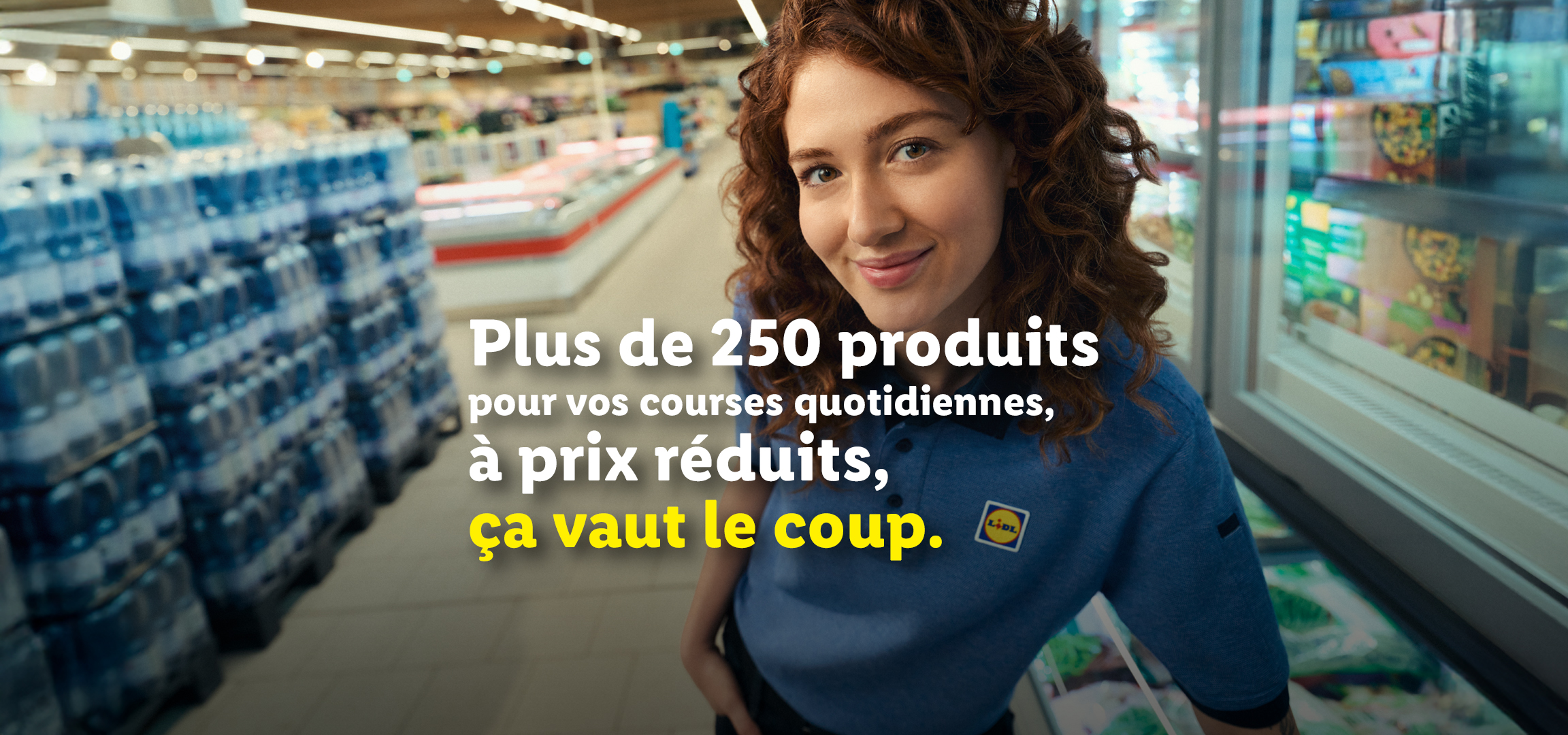 Une employée de supermarché souriante avec des palettes de bouteilles d'eau et du texte promotionnel.