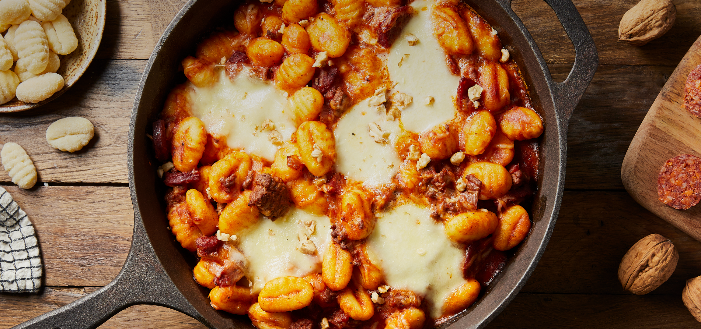 Gnocchis au fromage et à la sauce tomate dans une poêle, avec du chorizo et des noix.