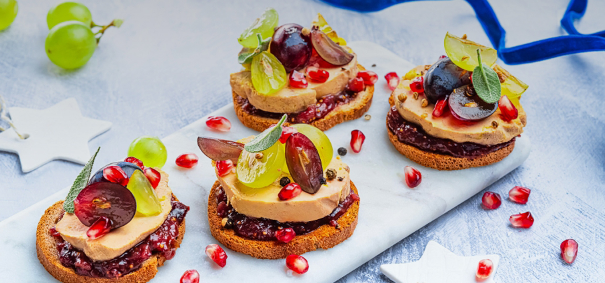 Canapés de foie gras avec confiture de figues, raisins et grenades sur une planche de marbre.