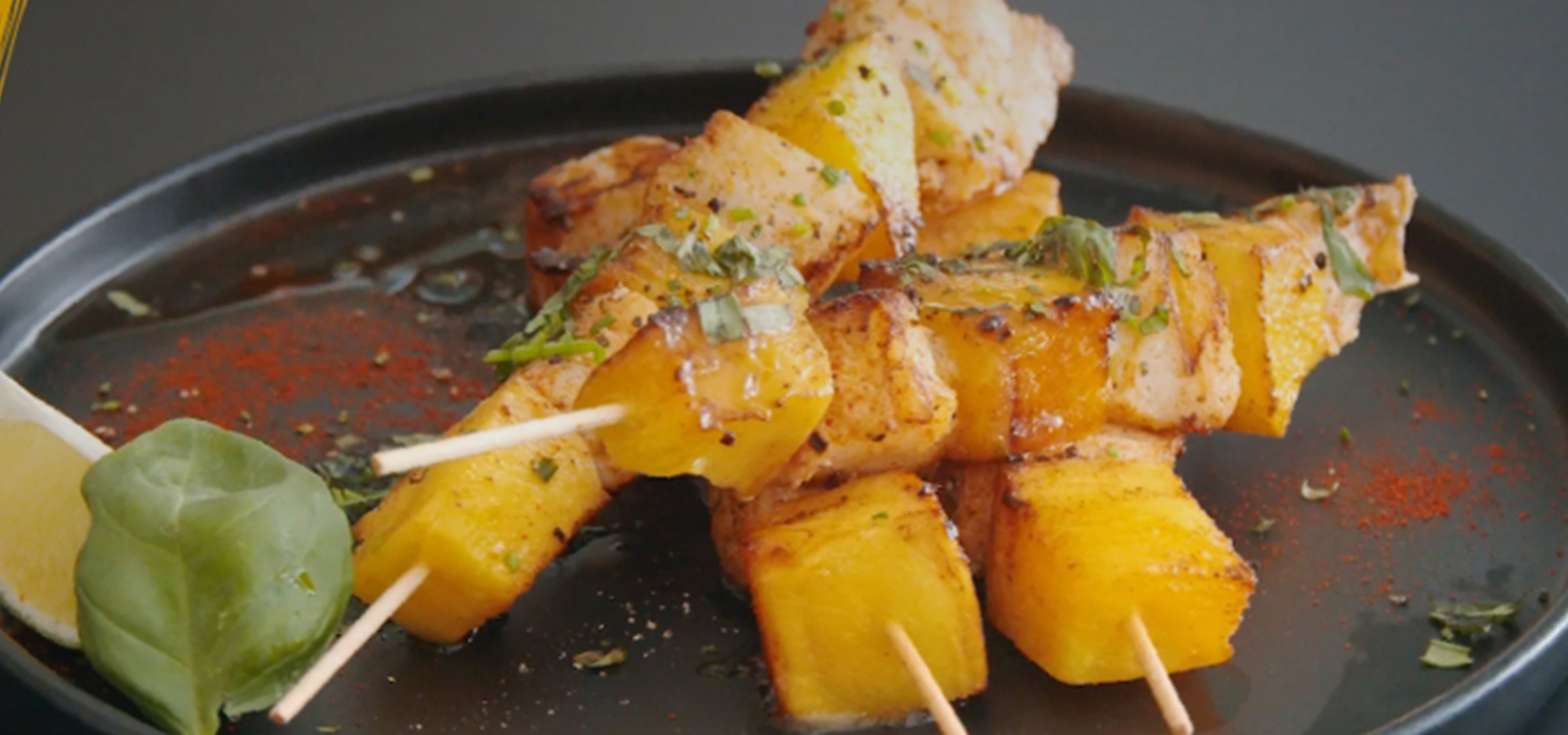 Brochettes de poulet et ananas grillés, garnies d'herbes et de paprika.