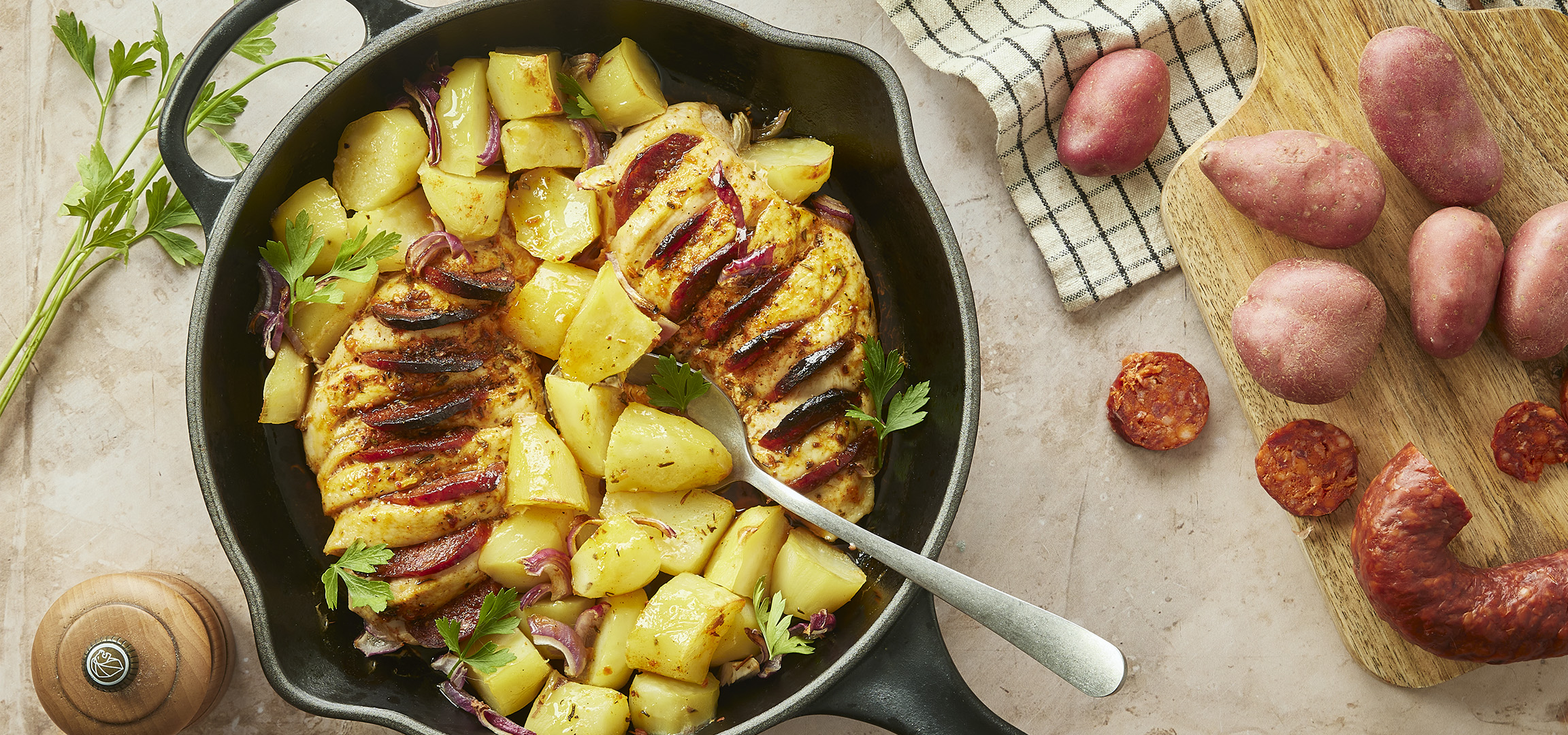 Poulet grillé avec pommes de terre et oignons rouges dans une poêle, avec des pommes de terre et du chorizo.