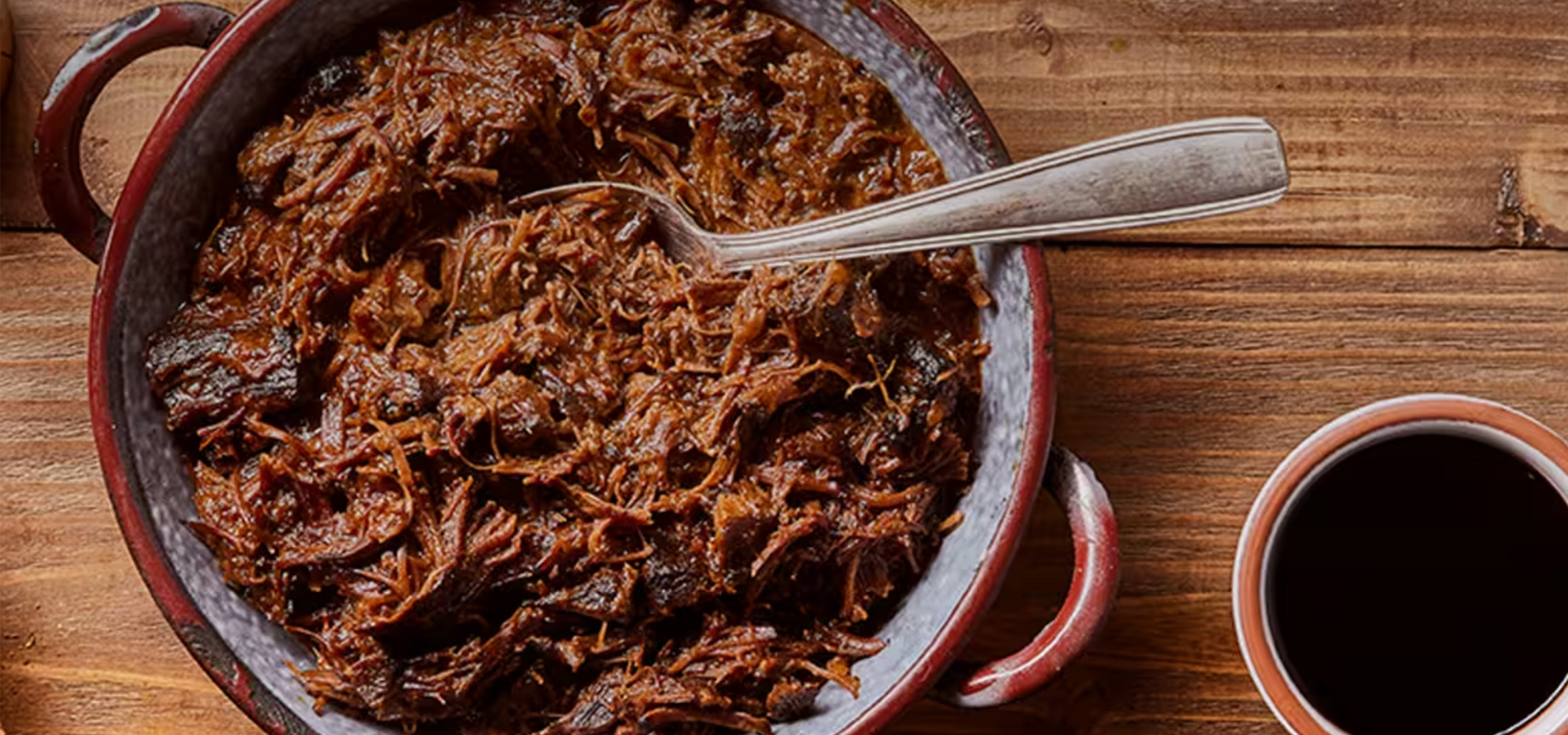 Plat de viande effilochée avec une tasse de café et des chips sur une table en bois.