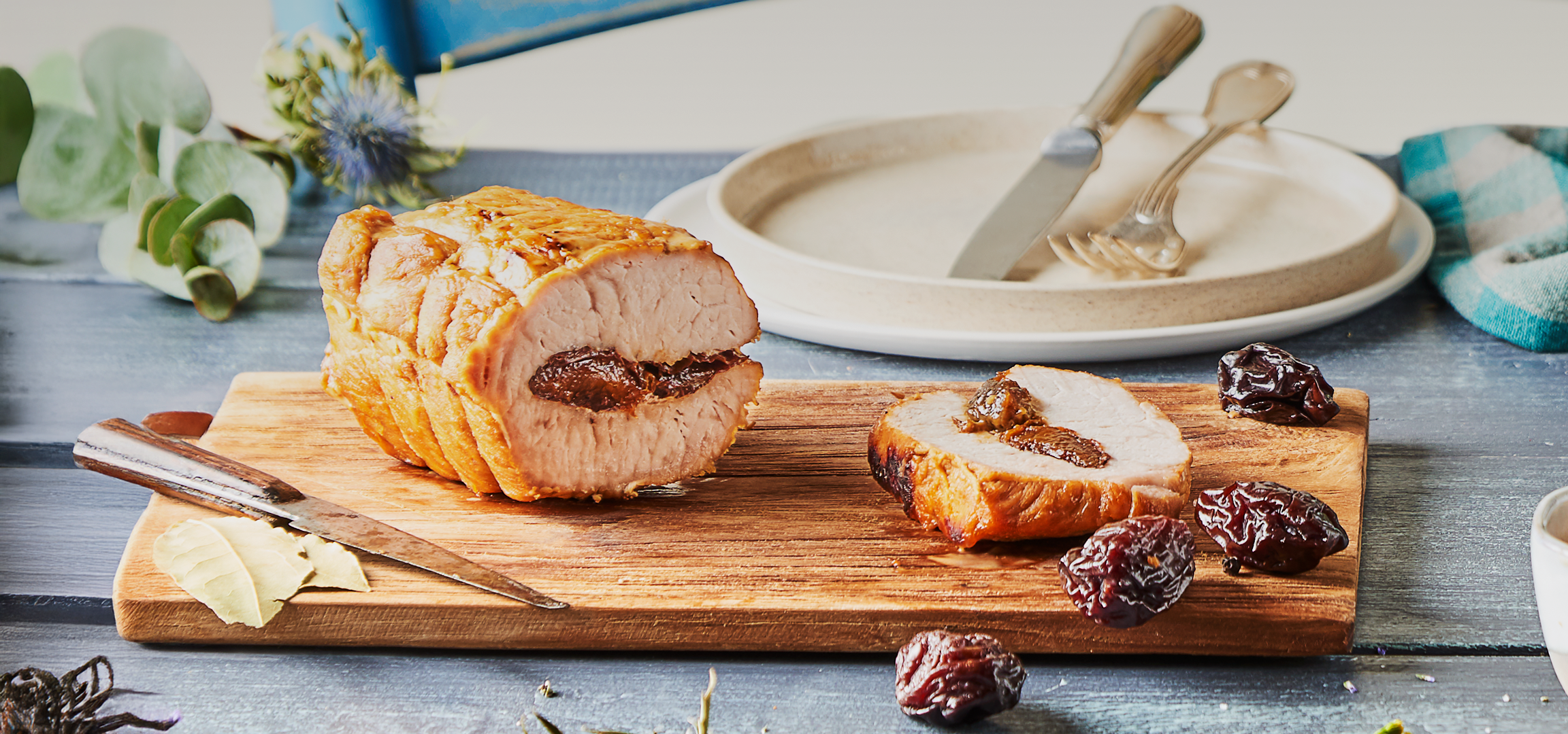 Rôti de porc farci aux pruneaux, servi avec des pommes de terre et des pruneaux.