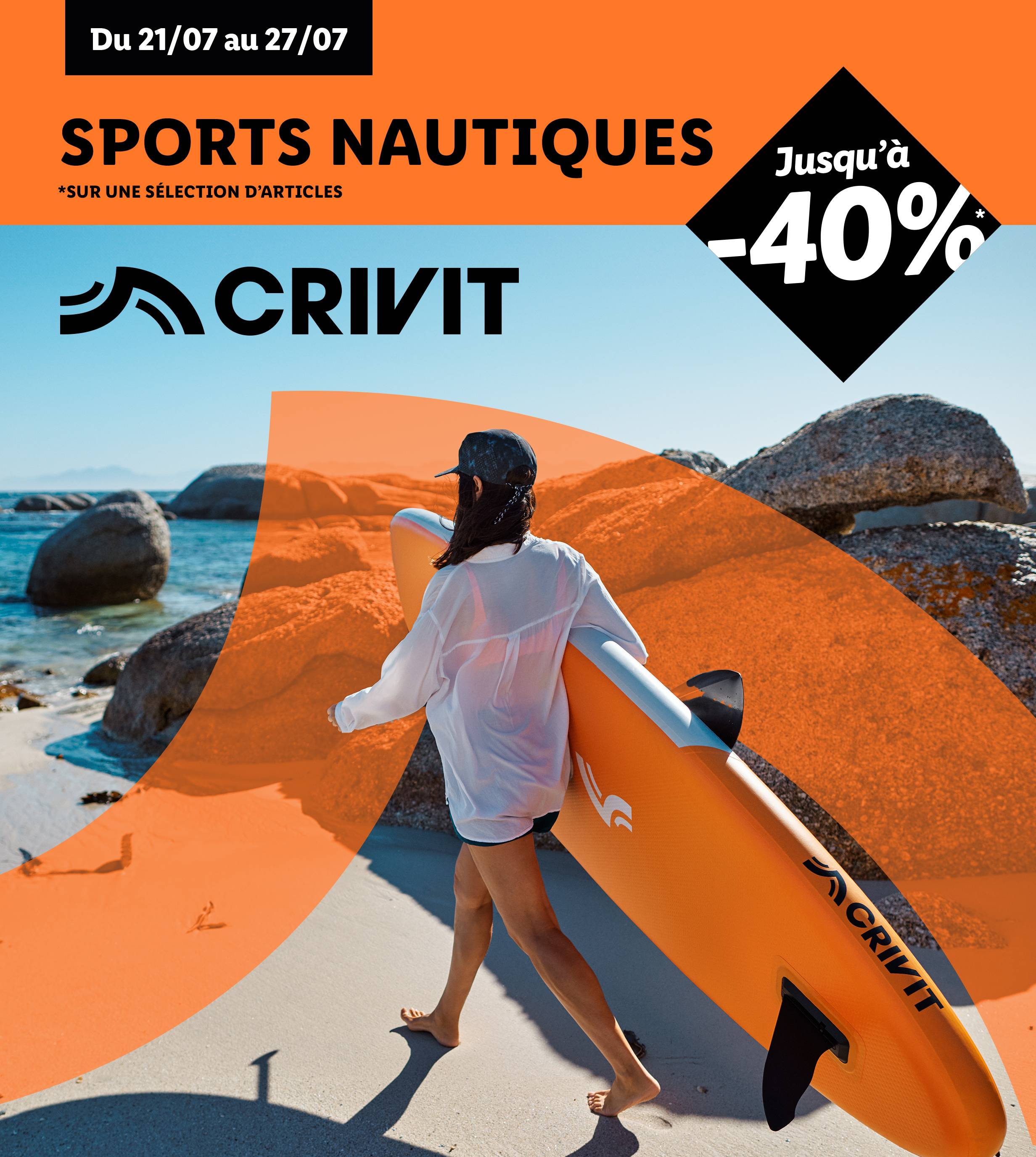 Une femme transporte une planche de paddle gonflable Crivit sur une plage.