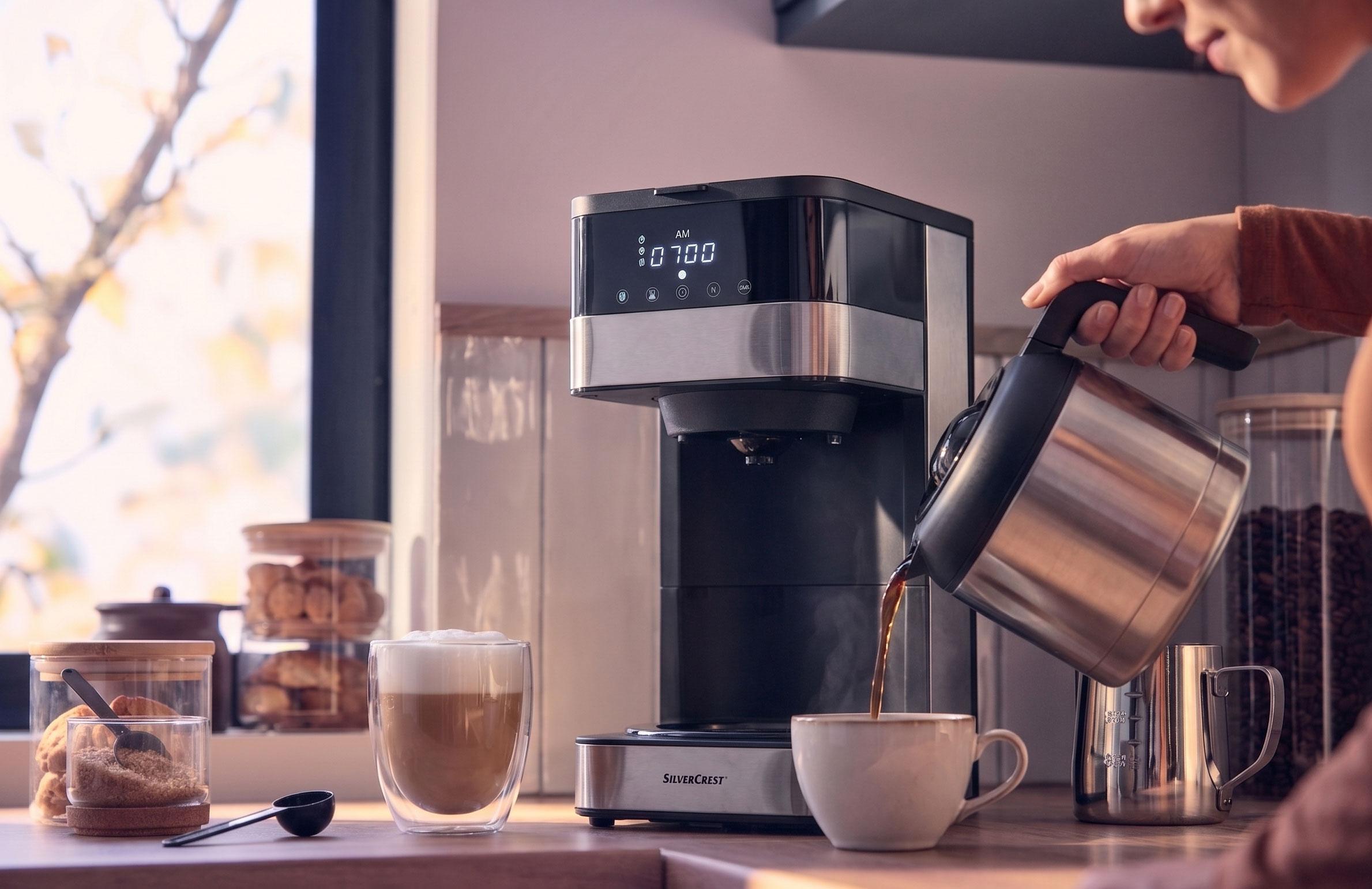 Machine à café versant du café dans une tasse, avec un latte et des biscuits sur le comptoir.
