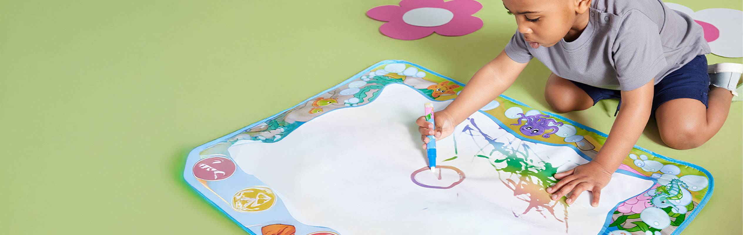 Un jeune enfant utilise un tapis à dessin aquatique pour créer des œuvres d'art.