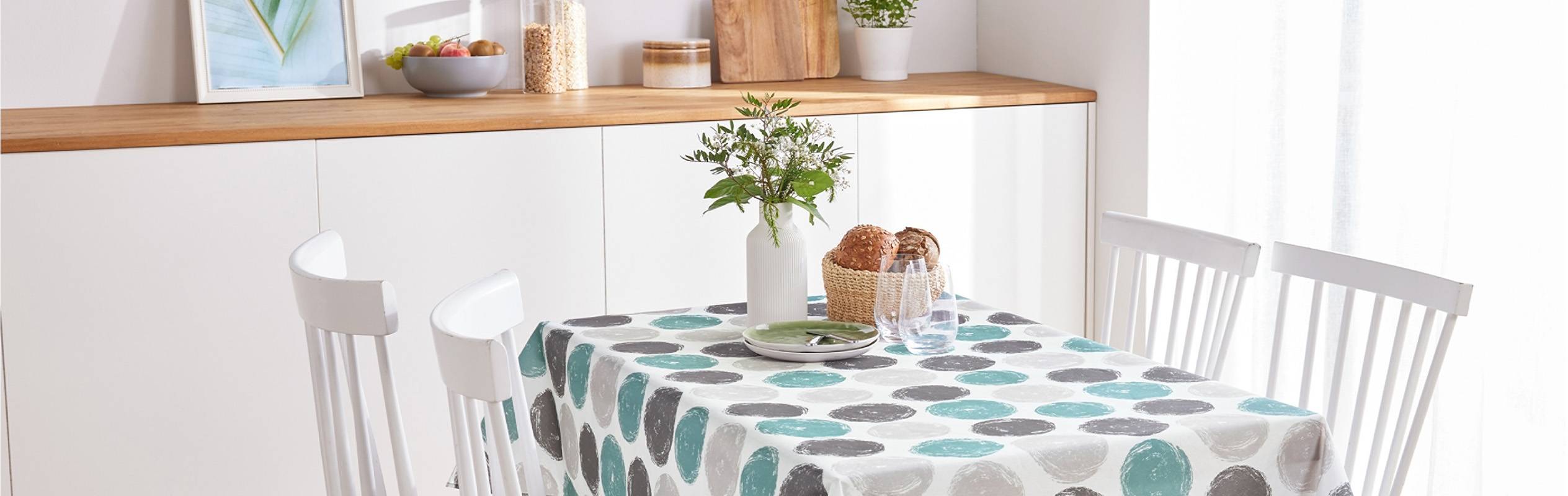 Une nappe à motifs circulaires gris et turquoise orne une table de salle à manger blanche.