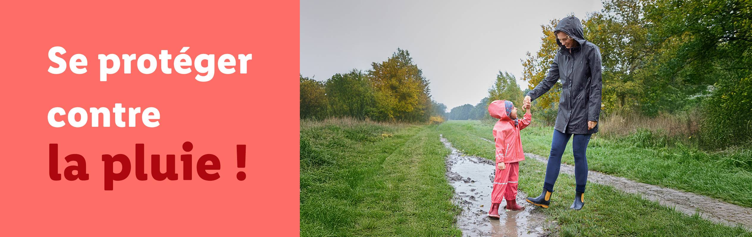 Une femme et un enfant en cirés et bottes de pluie sur un chemin boueux.