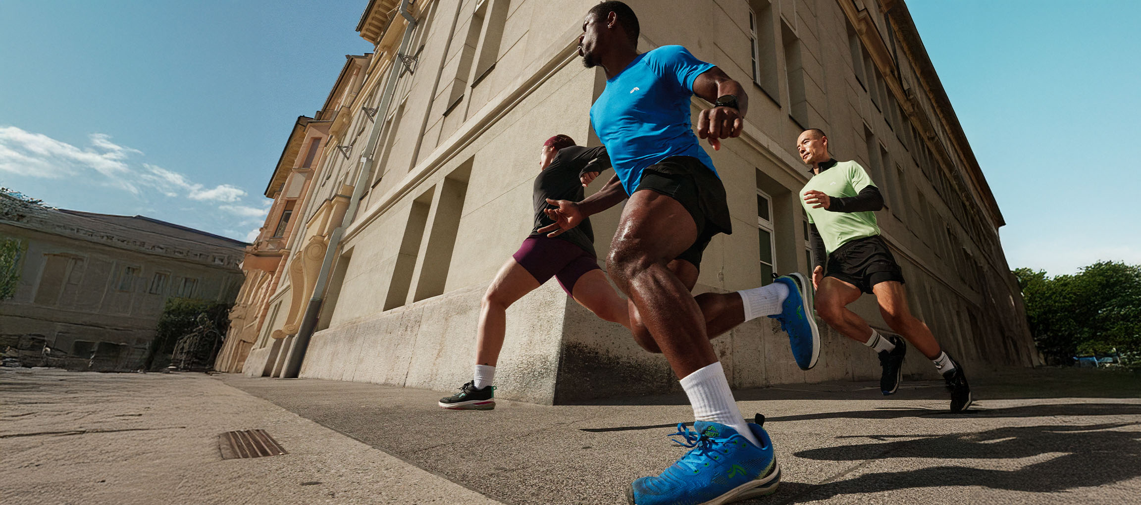 Trois coureurs en tenue de sport courant dans une rue de la ville.