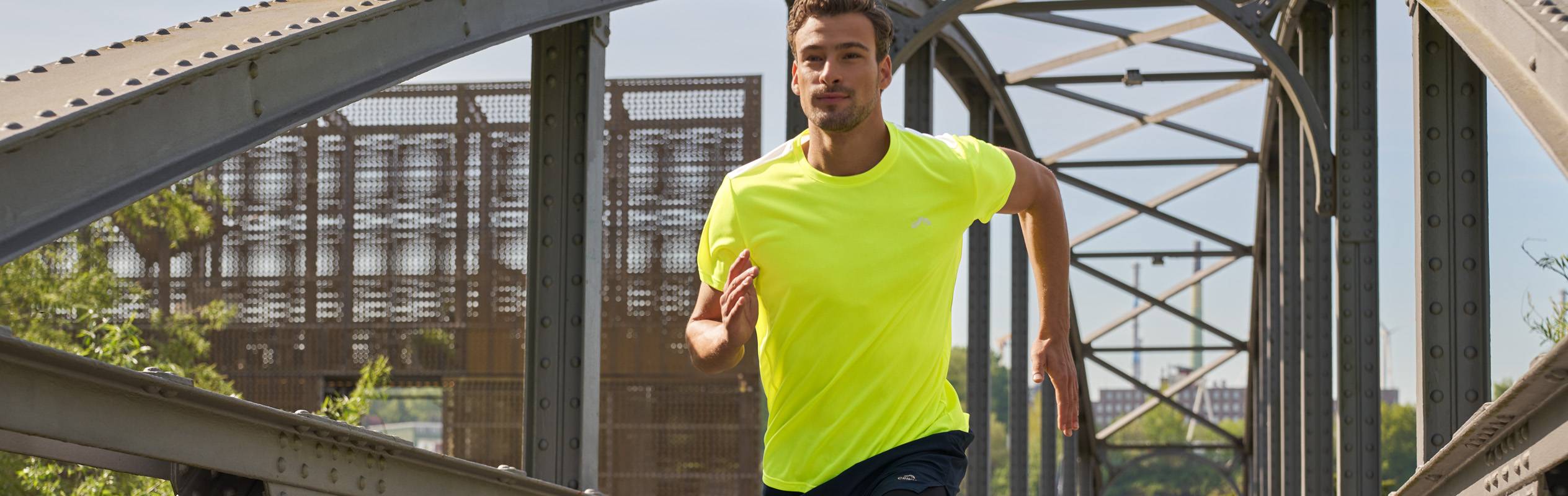 Un homme court sur un pont en portant un t-shirt jaune vif.