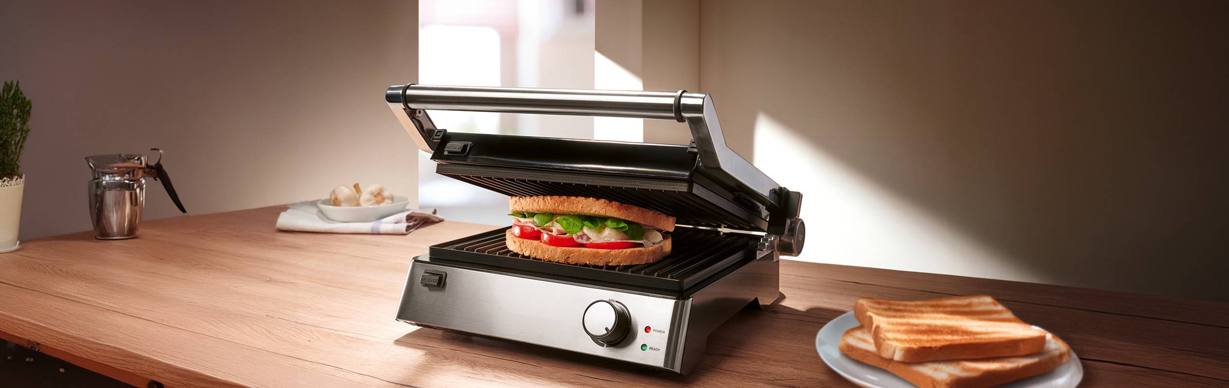 Un grille-sandwich Klarstein prépare un sandwich savoureux sur une table en bois.