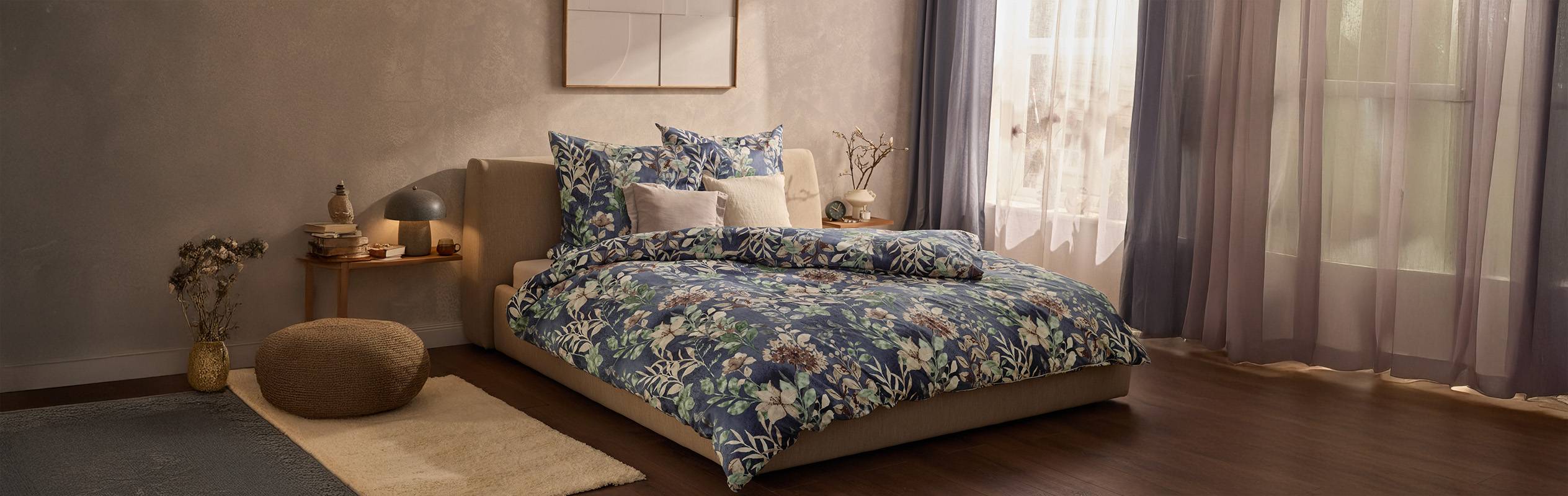 Chambre à coucher avec un lit double, une literie à motifs floraux bleus, une table de chevet et des rideaux.
