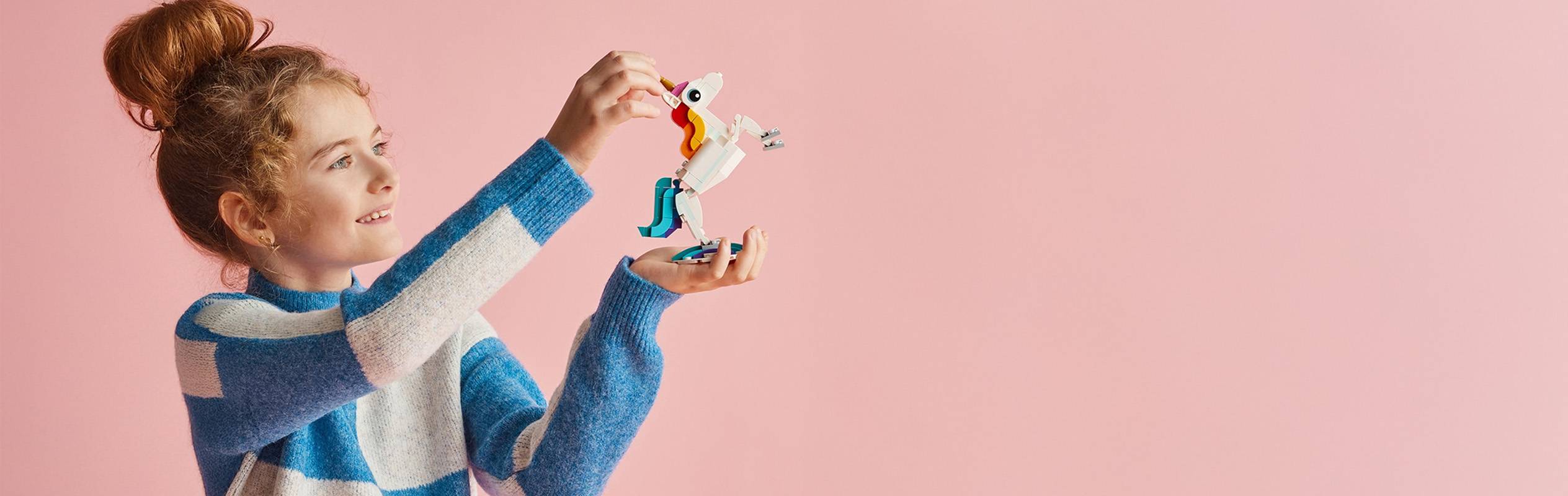 Une fillette aux cheveux roux joue avec un jouet licorne LEGO.
