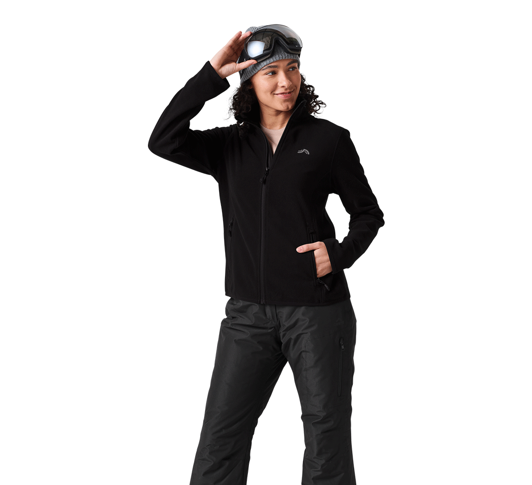 Femme en veste polaire noire, pantalon de ski et masque de ski.