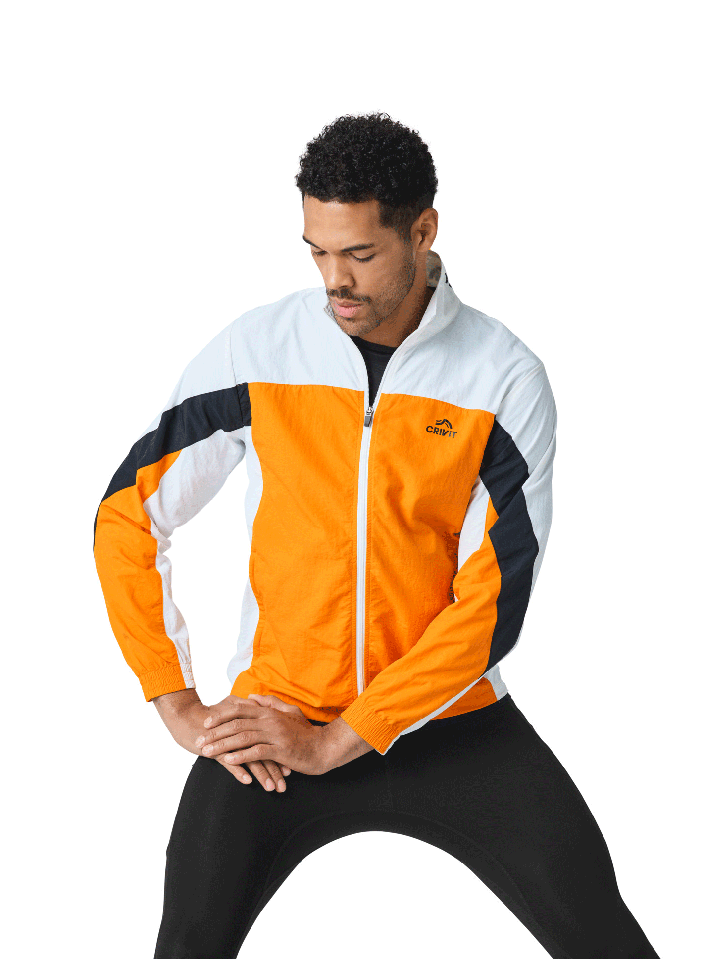 Homme en veste de sport orange, blanche et noire, et legging noir, en position d'étirement.