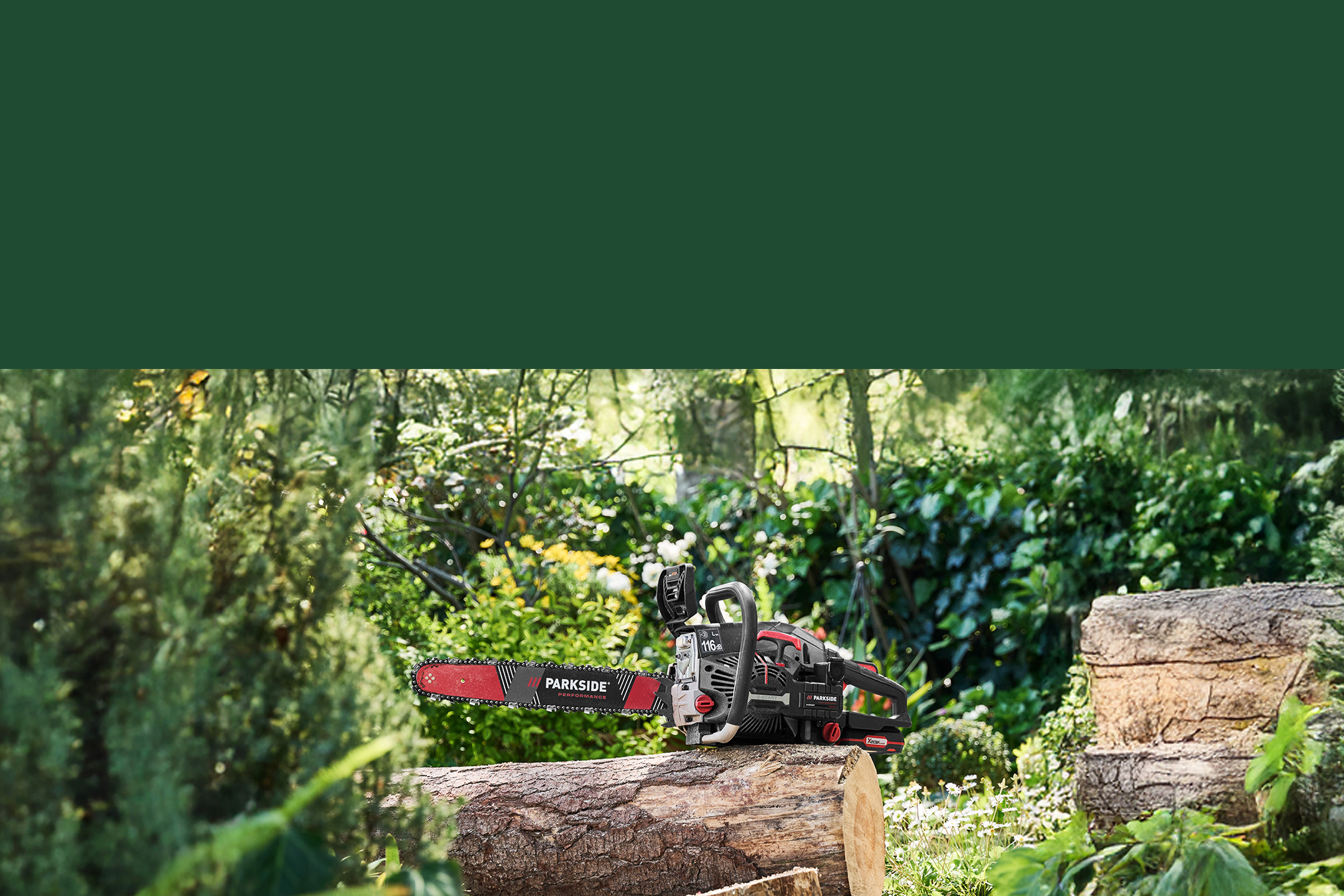 Tronçonneuse posée sur une bûche dans un jardin verdoyant.
