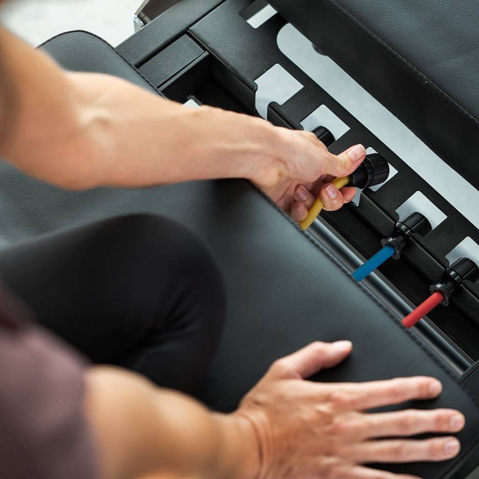Personne ajustant des bandes de résistance sur un banc d'exercice.