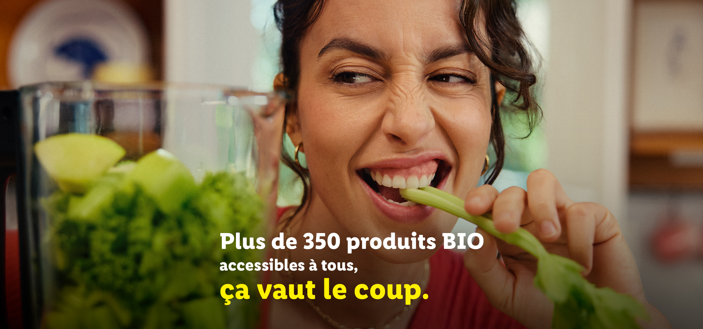 Une femme mange du céleri avec le texte 'Plus de 350 produits BIO accessibles à tous, ça vaut le coup.'