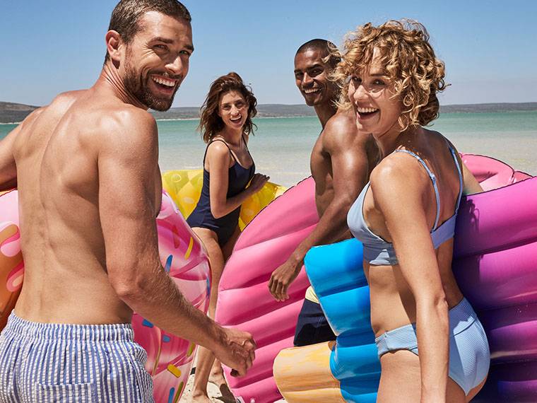 Des amis s'amusent à la plage avec des flotteurs gonflables en forme de glaces et de beignets.
