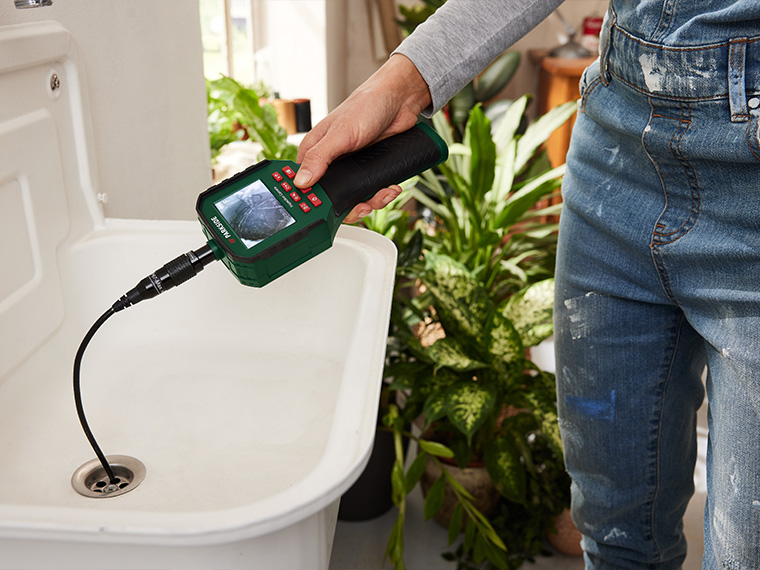 Une personne utilise une caméra d'inspection de canalisation MAKSITE pour inspecter un évier.