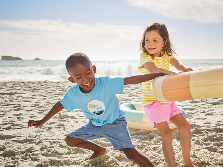 Deux enfants jouent sur la plage avec un grand flotteur en forme de glace.