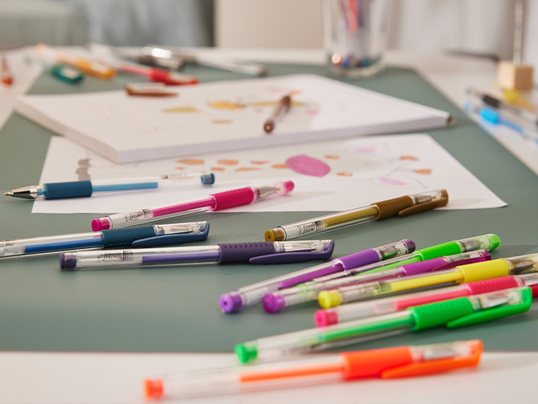 Des stylos gel colorés et des dessins d'enfants sur une table.