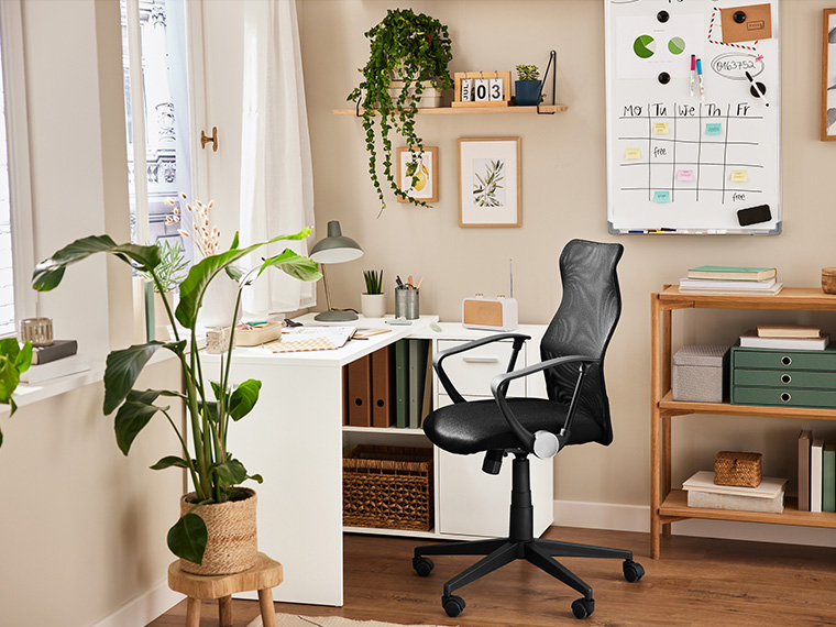 Un bureau moderne avec chaise de bureau ergonomique noire en maille, plantes et organisateurs.