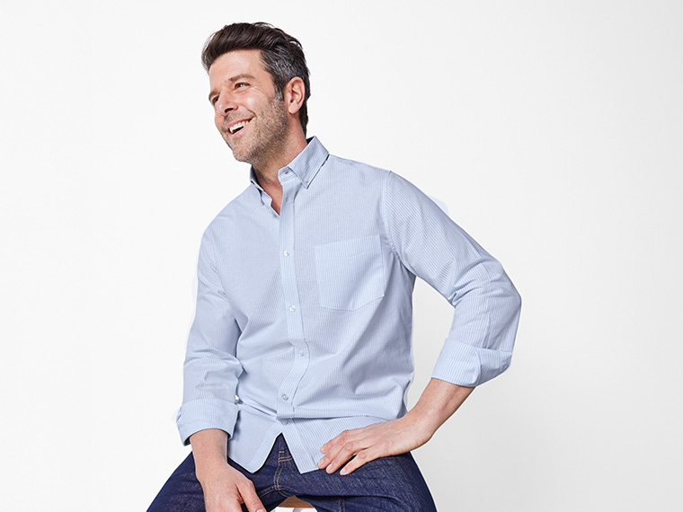 Homme souriant en chemise rayée bleue et jean.