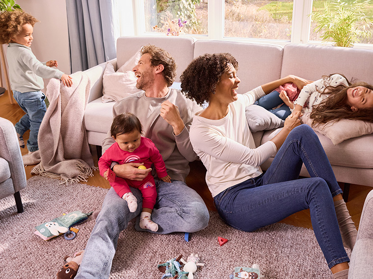 Une famille heureuse et diversifiée joue dans un salon confortable avec des meubles et des jouets.