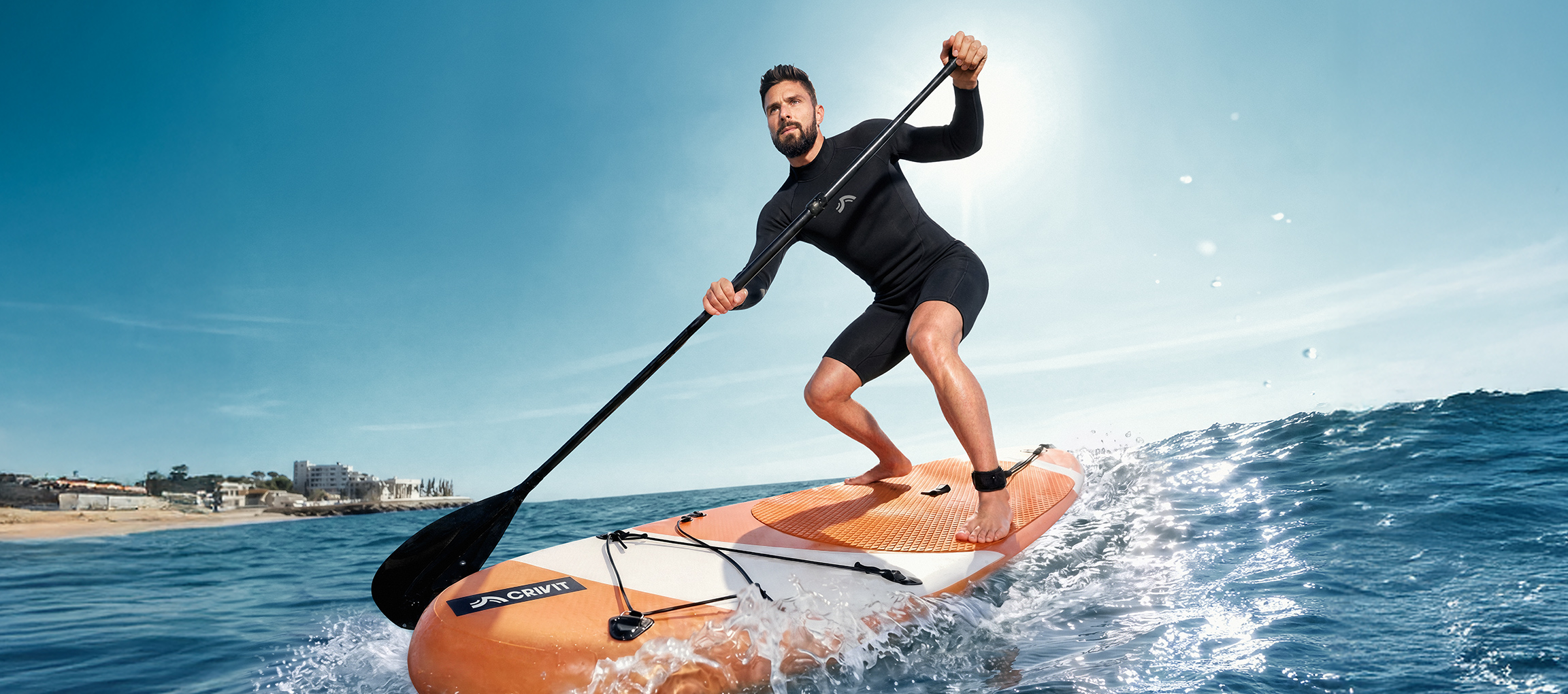 Homme en combinaison de plongée faisant du stand up paddle sur l'eau.